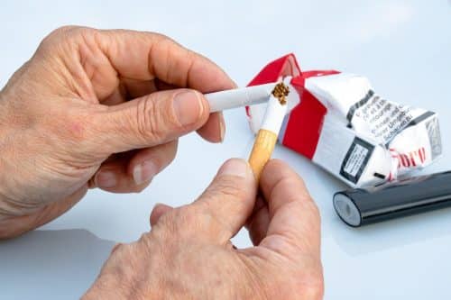 Action d'arrêter de fumer : mains brisant une cigarette, illustrant l'accompagnement par l'hypnose pour se libérer du tabac à Saint-Léger-les-Vignes