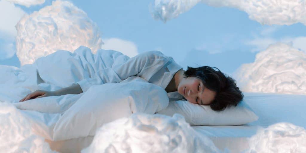 Femme dormant paisiblement sur des nuages, illustration du sommeil réparateur retrouvé grâce à l'hypnose et au reiki à Saint-Léger-les-Vignes.