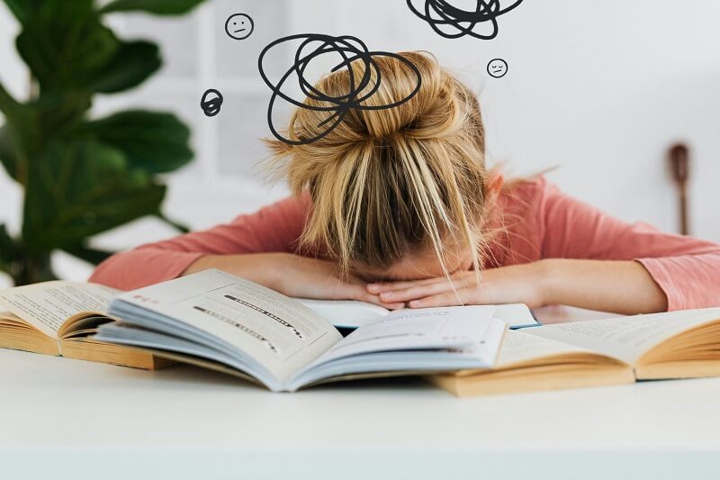Illustration du stress et de l'anxiété : enfant la tête dans les livres, symbolisant les blocages scolaires et émotionnels traités par l'hypnose à Saint-Léger-les-Vignes