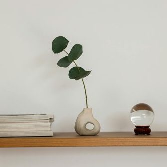 Sleek and modern shelving with a ceramic vase holding leaves, books, and crystal spheres for decor.